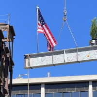 beam on crane being lifted onto building